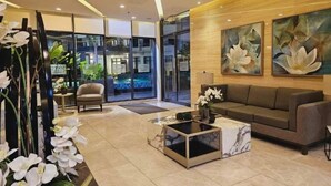 A modern lobby with a sofa, a coffee table, and a chair. There are large windows and a view of a pool. - Cozy and Comfy Retreat with Balcony (Paranaque)