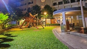 A well-lit outdoor area with a playground, a covered seating area, and a building in the background. - Cozy and Comfy Retreat with Balcony (Paranaque)