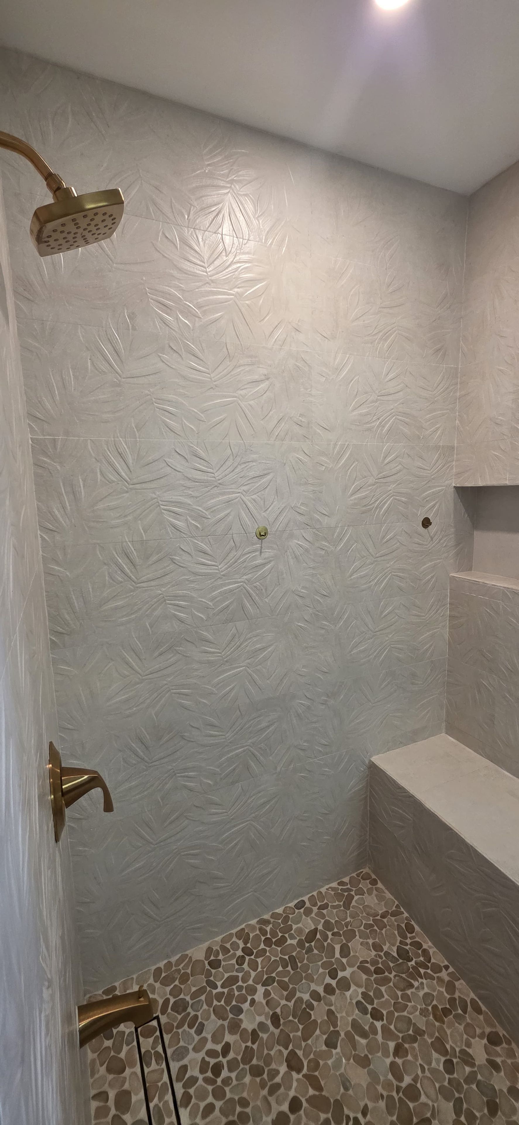 A shower area with a textured wall and a pebble-patterned floor.