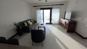 A modern living room with a sofa, a dining table, and a TV. - Stunning Oceanview Condo Steps to Playa Flamingo w/ Pool, BBQ & Beach Access (Playa Flamingo)