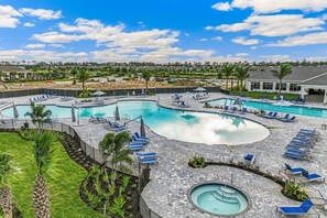 Una gran piscina al aire libre con varias pistas de natación y zonas de descanso con sillas y sombrillas azules.
