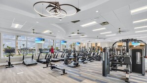 A modern gym with various exercise equipment, large windows, and a view of palm trees. - Babcock National Golf Club - 2 Bedroom Condo w/ Amenities in Babcock Ranch (Punta Gorda)
