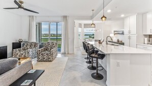 A modern kitchen with a large island, bar stools, and a dining area with a view. - Babcock National Golf Club - 2 Bedroom Condo w/ Amenities in Babcock Ranch (Punta Gorda)