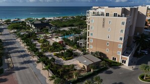 A multi-story hotel with a pool area, surrounded by palm trees and a beach view. - Ocean views of #1 rated Eagle Beach from 5th floor (Eagle Beach, Oranjestad)