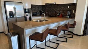 A modern kitchen with a stainless steel refrigerator, built-in oven, and coffee maker. - Ocean views of #1 rated Eagle Beach from 5th floor (Eagle Beach, Oranjestad)