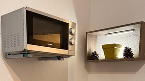 A compact kitchenette with a microwave, a small shelf with decorative items, a bowl of croissants, a glass of orange juice, and a chair. - Studio Cannes, 350 m from the sea (Cannes)