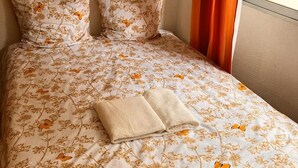 A neatly made bed with floral bedding, two pillows, and a folded towel. - Studio Cannes, 350 m from the sea (Cannes)