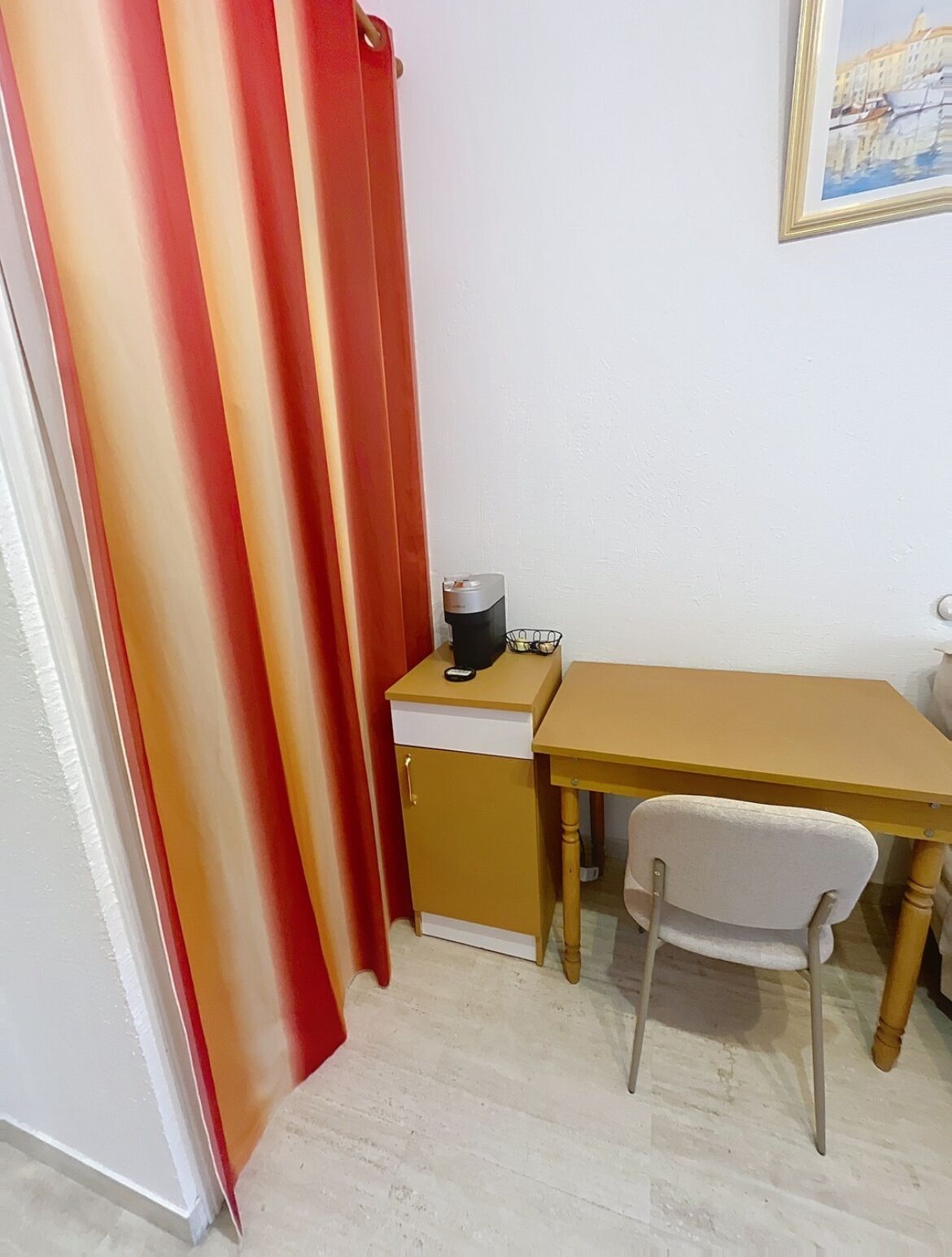 A small room with a desk, chair, and a coffee machine.