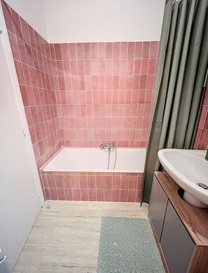 A bathroom with a bathtub, a sink, and tiled walls. - Studio Cannes, 350 m from the sea (Cannes)