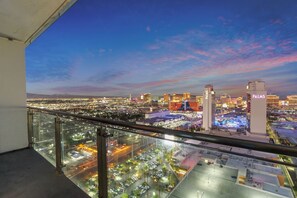 A cityscape view from a balcony with a clear sky, featuring prominent buildings including a tall structure with "PALMS" signage. - Luxury Strip-View Studio • No Resort Fees • Free Parking! (Las Vegas)
