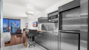 Une cuisine moderne dotée d’appareils électroménagers en acier inoxydable, un coin repas avec un tabouret de bar et une vue sur la ville grâce à de grandes fenêtres.