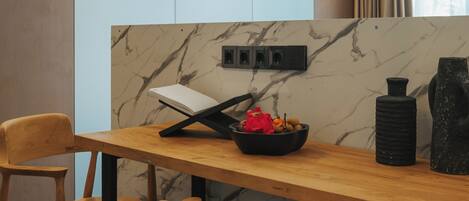 A modern dining area with a wooden table and chairs, a marble backsplash, and a black vase.