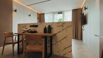 Una cocina moderna con salpicadero de mármol, sillas de madera, una mesa de comedor y un televisor montado en la pared.