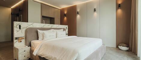 Un dormitorio moderno con cabecera de mármol, una cama grande, mesitas de noche e iluminación empotrada.