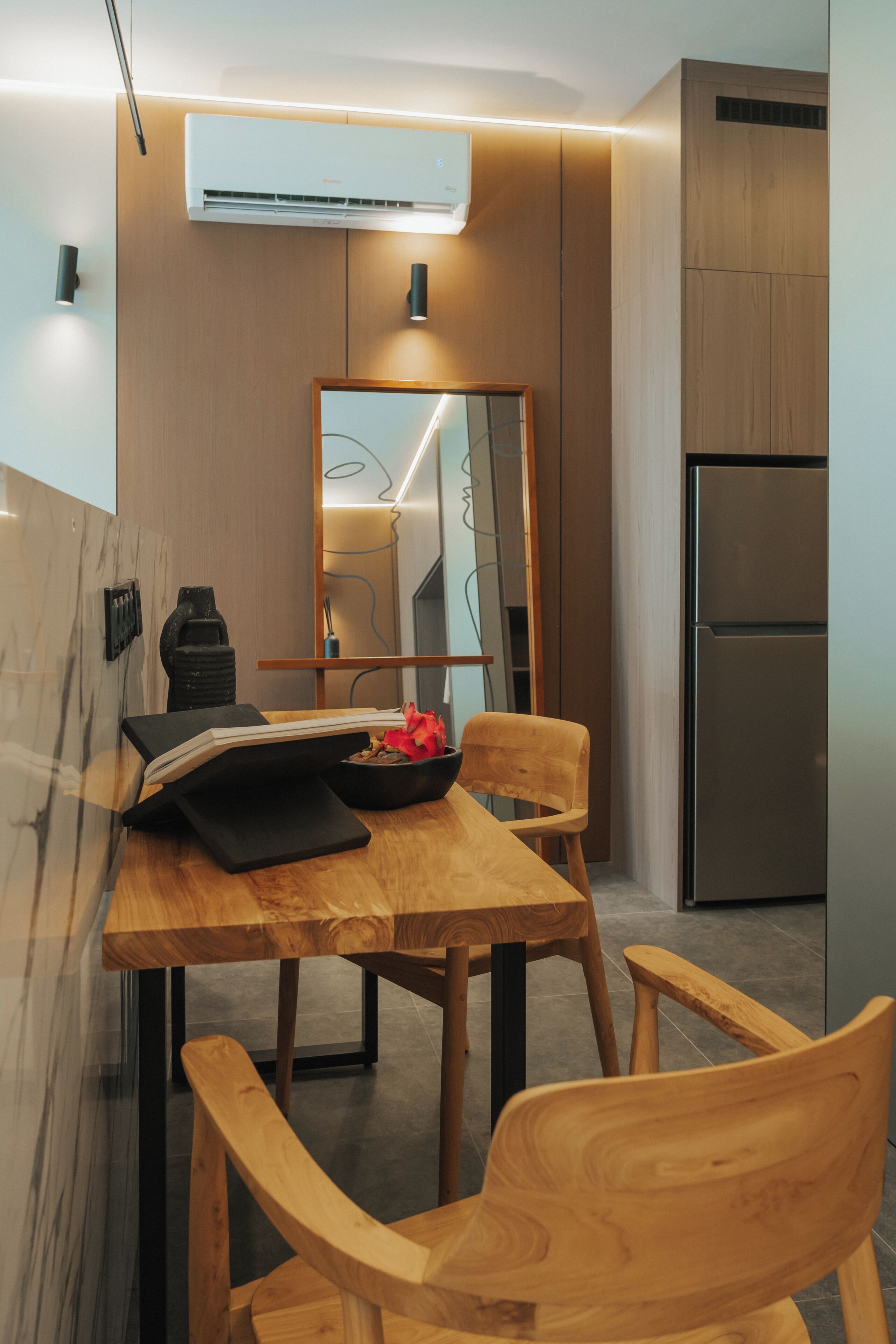 A modern kitchen with wooden cabinetry, a built-in stove, and a stainless steel refrigerator.