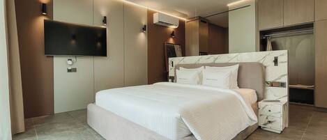 A modern bedroom with a large bed, a flat-screen TV mounted on the wall, and a built-in wardrobe.