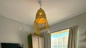 Un dormitorio con una cama grande, un televisor en un estante, un armario y una ventana con cortinas.