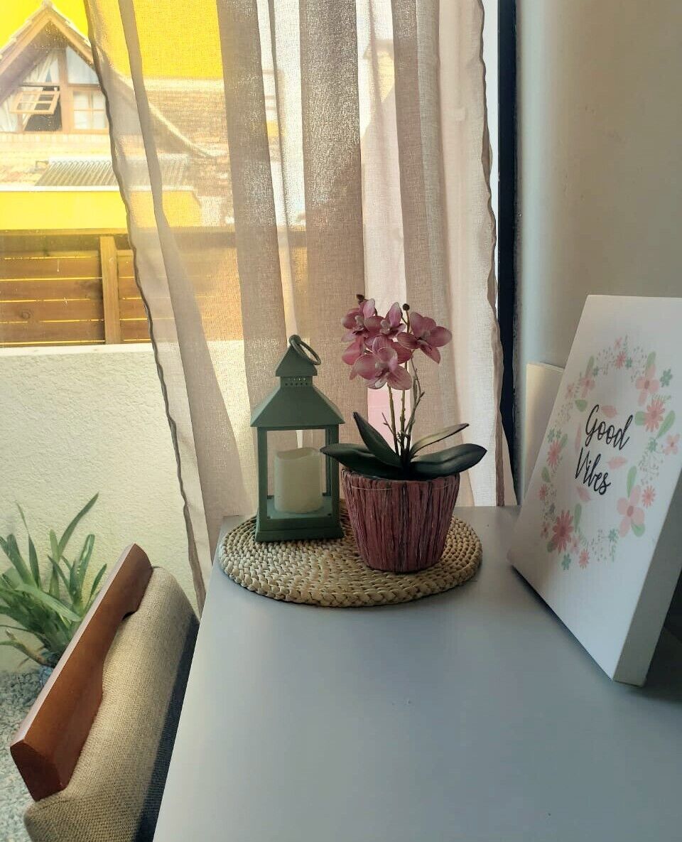 A small table with a potted plant, a lantern, and a card with 'Good Vibes' written on it.