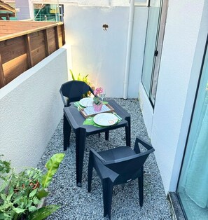 Ein kleiner Balkon mit Sitzgelegenheit für zwei Personen, einem Tisch, einem Stuhl und einem Blumentopf.