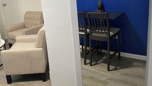 Une pièce avec un mur d’accent bleu, une table à manger avec des chaises et un fauteuil beige.