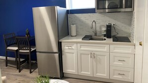 Une cuisine avec des meubles blancs, un réfrigérateur en acier inoxydable, un four à micro-ondes et un évier avec un robinet.
