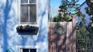 Una casa blava amb una porta de fusta, una finestra amb una caixa de flors i una corona a la porta.