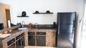 Una cocina con un refrigerador negro, un lavamanos y una estufa. Hay armarios y una encimera.