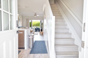 Un couloir avec un escalier, un coin cuisine et un espace repas.