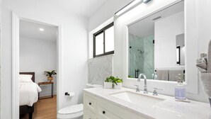A modern bathroom with a large mirror, white cabinetry, and a marble backsplash. - Villa Azur 8BR Outdoor Oasis with Poolside Bar (Miami)