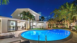 A modern house with a swimming pool, large windows, and outdoor furniture. - Villa Azur 8BR Outdoor Oasis with Poolside Bar (Miami)
