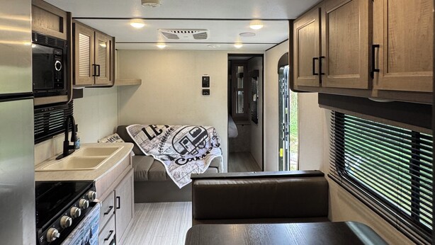 A compact RV kitchen with a stove, sink, and cabinets.