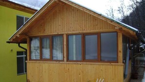 Une cabane en bois avec un toit en pente, de grandes fenêtres et un petit espace porche.