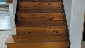 Een houten trap met een leuning, die naar een verdieping leidt.