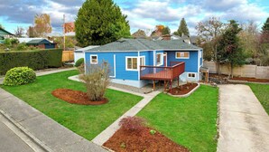 Een blauw huis met twee verdiepingen, een veranda, een oprit en een verzorgd gazon.