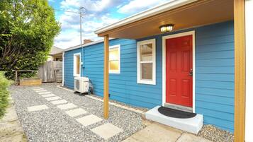 A blue house with a red door, a covered porch, and a gravel pathway.