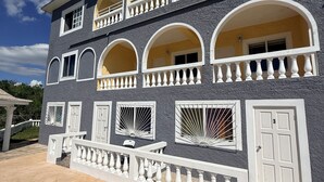 A multi-story building with balconies, arched windows, and a gated entrance. - Superstar Living : Beautiful 3-Bed Room Suite with Balcony and Sea View (Treasure Beach)