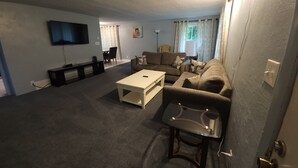 A living room with a flat-screen TV, a sofa, a coffee table, and a TV stand. - Relaxing Ranch (sodus)