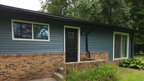 A single-story house with a brick foundation and a dark blue siding exterior. - Relaxing Ranch (sodus)