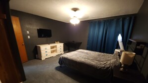A bedroom with a bed, dresser, desk, and a TV on the wall. - Relaxing Ranch (sodus)