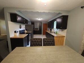 Una cocina compacta con armarios oscuros, una isla central con asientos y un microondas.