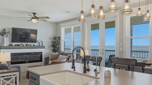 Une cuisine moderne dotée d’un îlot central, de luminaires suspendus et d’un ventilateur de plafond.
