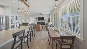 Une cuisine spacieuse dotée d’un îlot central, de chaises en bois et de luminaires suspendus.