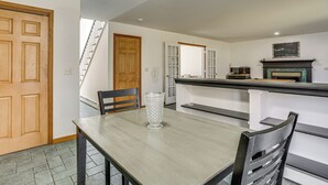 Uma sala de jantar com uma mesa de madeira, cadeiras e um vaso de vidro transparente.