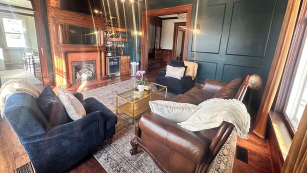 A spacious living room with leather sofas, a coffee table, and a fireplace.