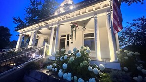 A white building with a porch, columns, and an American flag.
