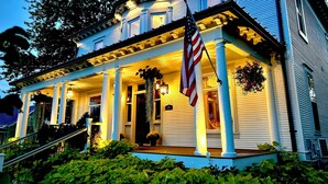 A two-story house with a porch, columns, and an American flag.