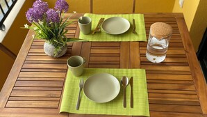 Una mesa de madera para comer con dos platos, cubiertos y un vaso de agua.
