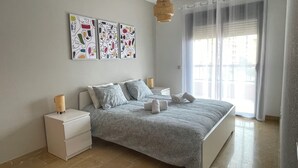 Un dormitorio con una cama grande, dos mesitas de noche, una lámpara de fibras naturales y una obra de arte abstracta en la pared.
