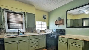Une cuisine avec des meubles de rangement verts, une cuisinière et un évier.