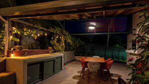 An outdoor patio with a wooden table and chairs, a built-in sink, and potted plants. - Mata e' Plátano Guest House Suite (Mata de Platano)